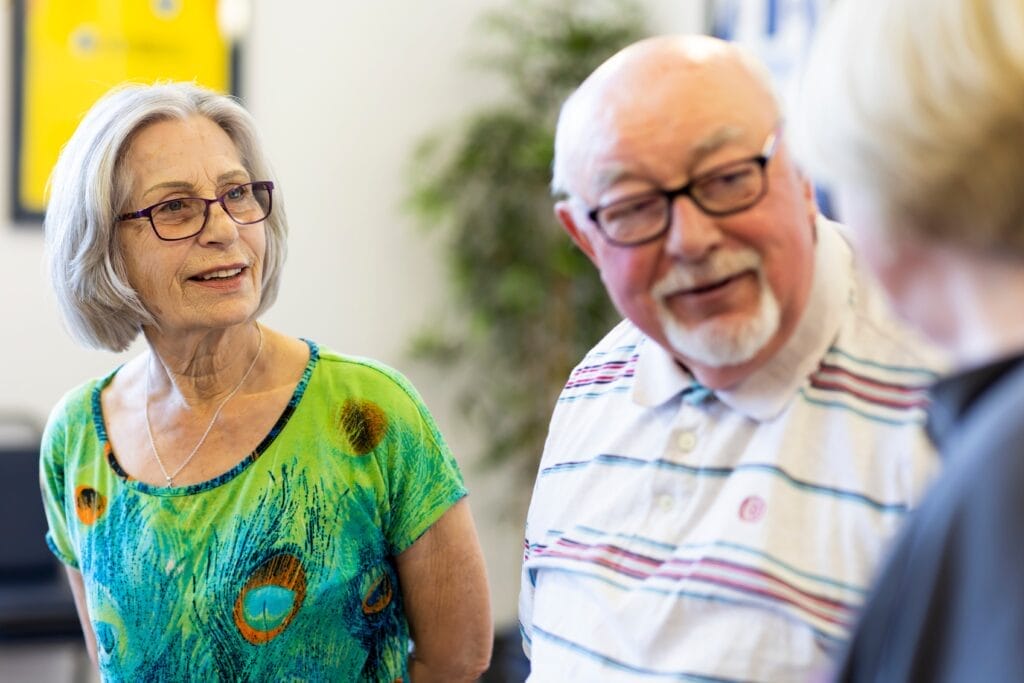 Two older women and an older man talking together
