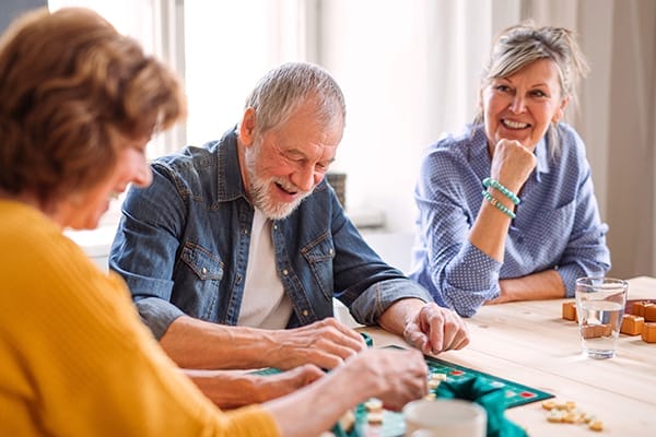 Group of senior people sitting at the table in community center club, playing board games.