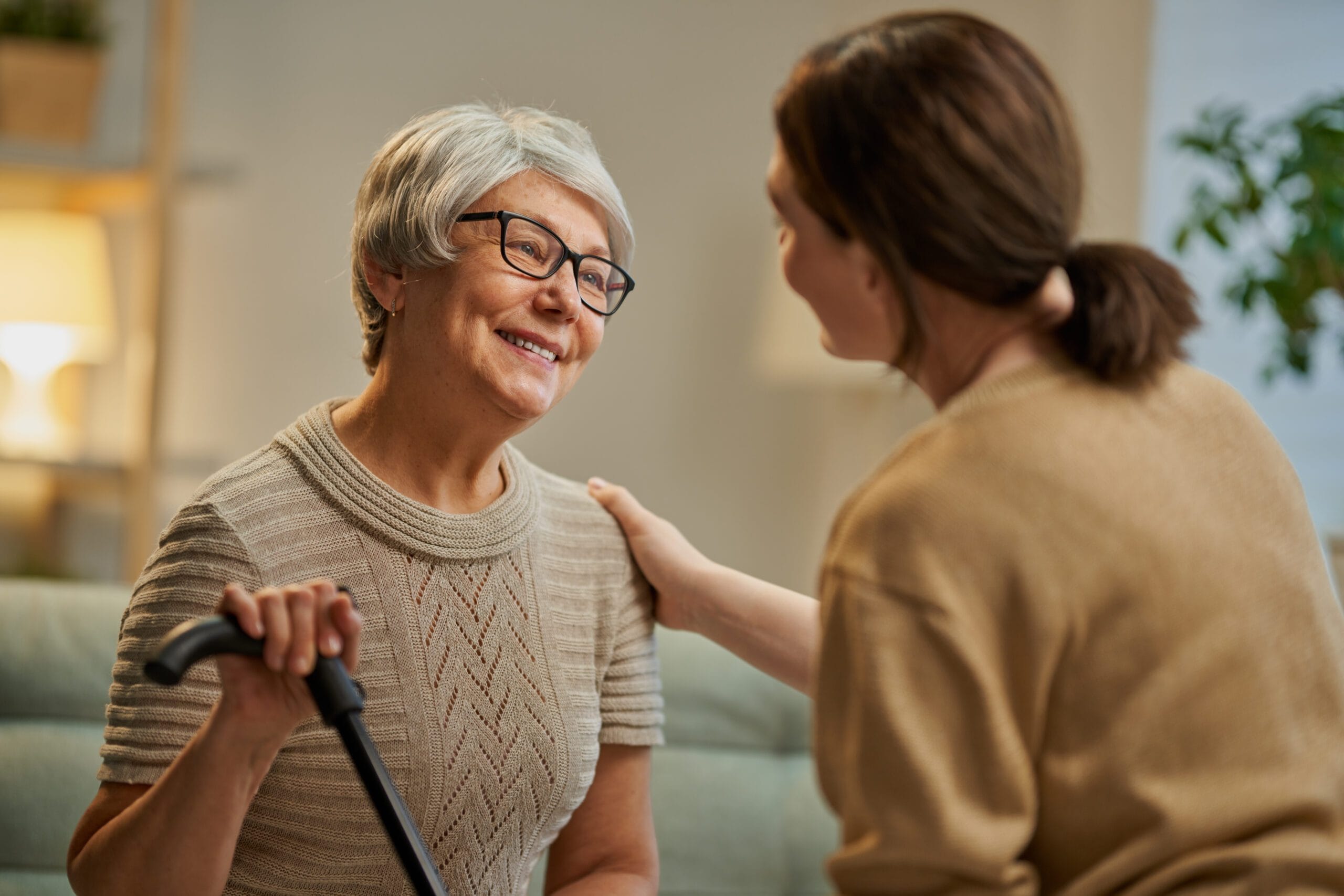 Happy patient and caregiver spending time together. Senior woman holding cane.