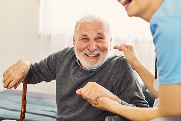 caregiver with senior man holding walking cane at home