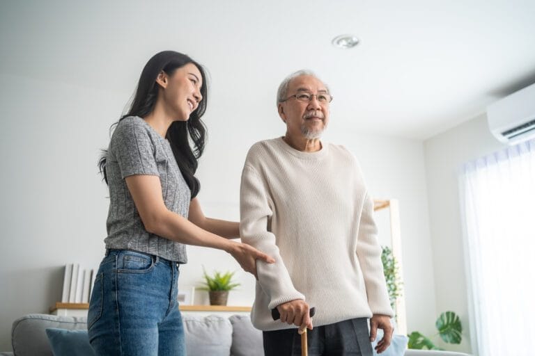 Asian young daughter support senior older man walk with walker at home