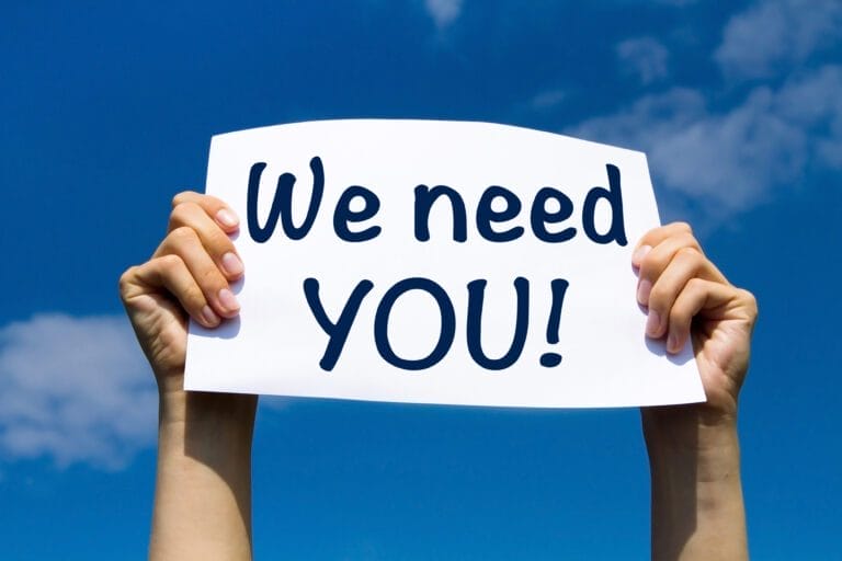 hands holding a sign reading we need you to the sky