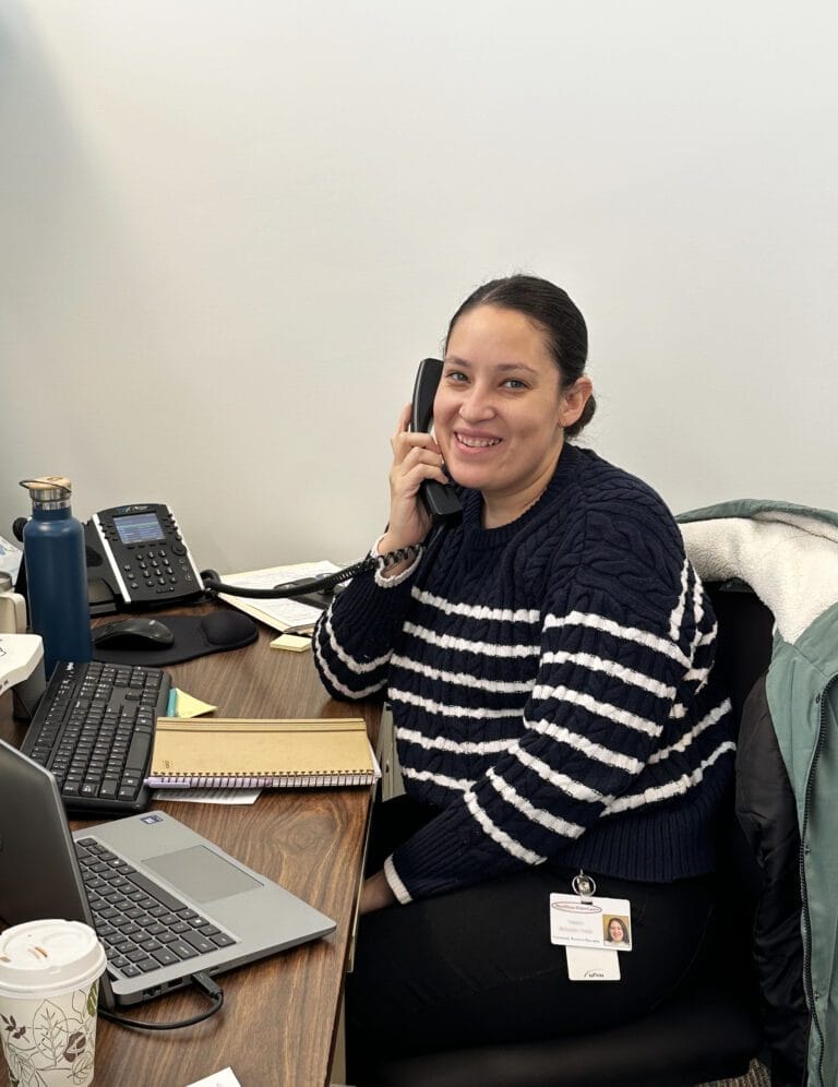 Smiling Community Resource Specialist at her desk talking on the phone