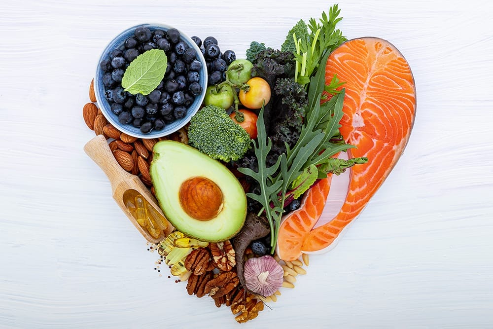 Heart shape of ketogenic low carbs diet concept. Ingredients for healthy foods selection on white wooden background. Balanced healthy ingredients of unsaturated fats for the heart and blood vessels.
