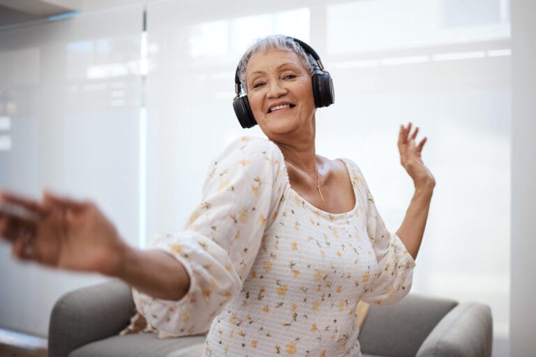 Shot of a senior woman dancing while using headphones at home.