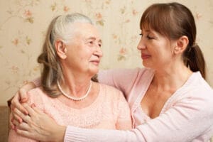 Happy family. Portrait of elderly woman and adult daughter happily looking at camera. Senior woman with their caregiver at home.