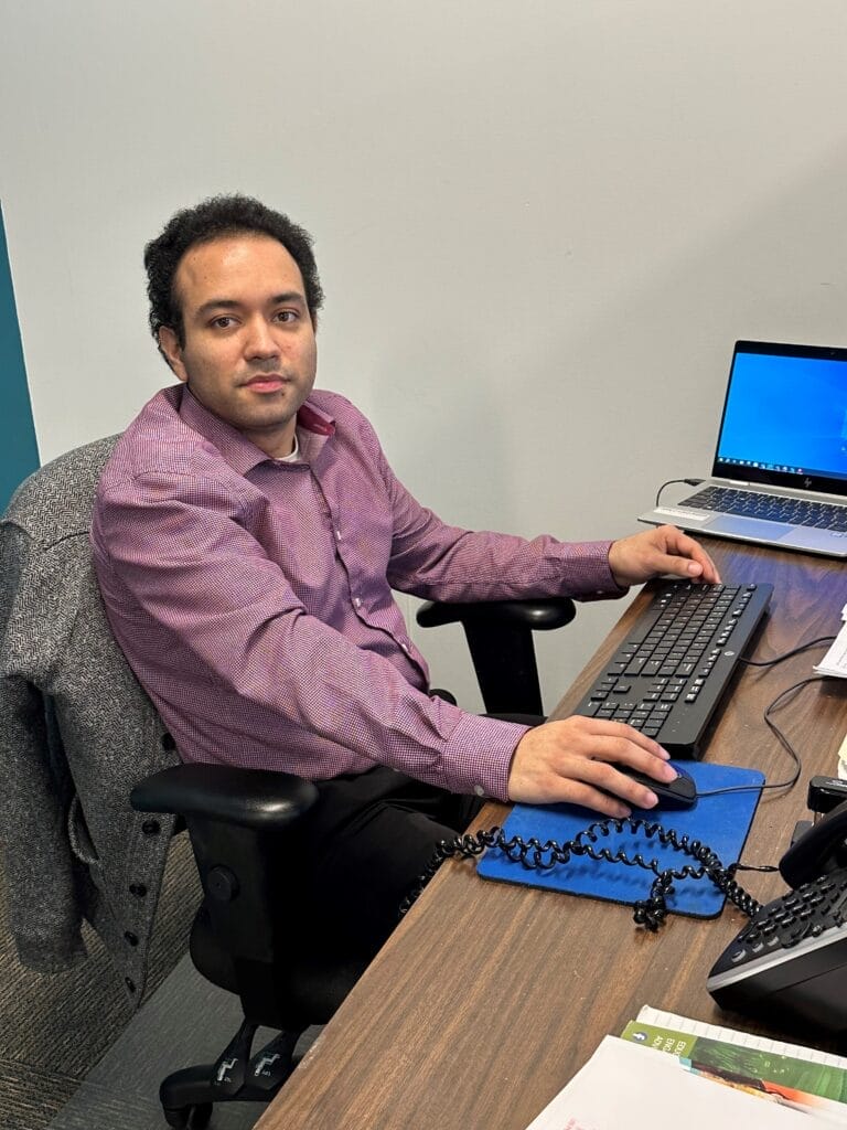 A Latino male Community Resource Specialist working at his desk